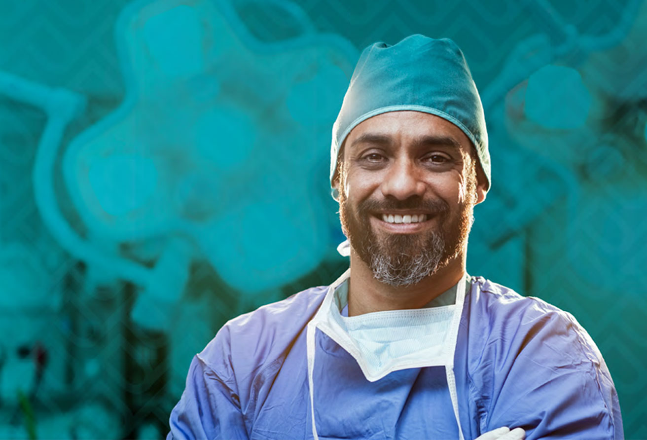 A surgeon smiles at the camera while standing in an operating room.