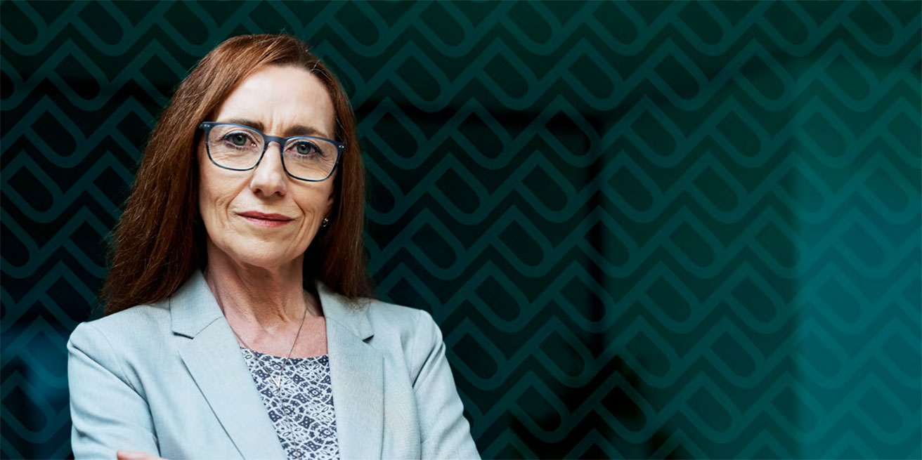 A woman wearing professional attire and glasses.