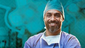 A surgeon smiles toward the camera while standing in an operating room.