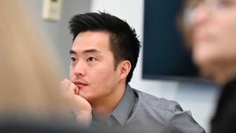 A man sits in an office setting with a thoughtful look on his face.