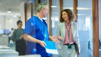 Two medical professionals converse over a medical chart.