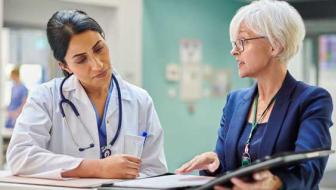 Two medical professionals converse over a medical chart.